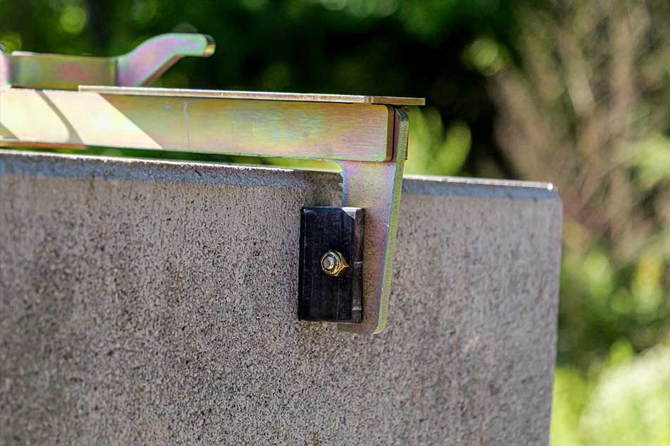 Metal bracket attached to a concrete wall with a blurred green background