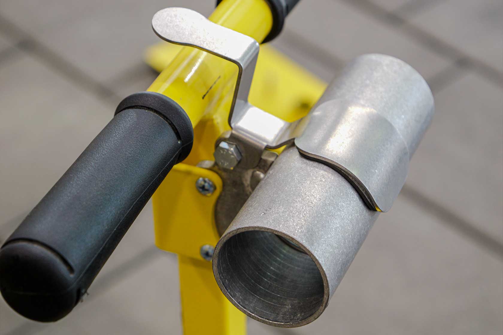 A close-up of a Vac Max Relief Valve attached to a yellow and black plumbing fixture, with a metallic finish on the valve and a rubber handle.